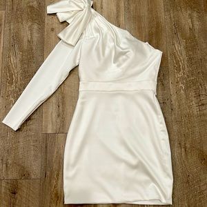 This fitted satin one-sleeve minidress is finished with a bow at the shoulder.